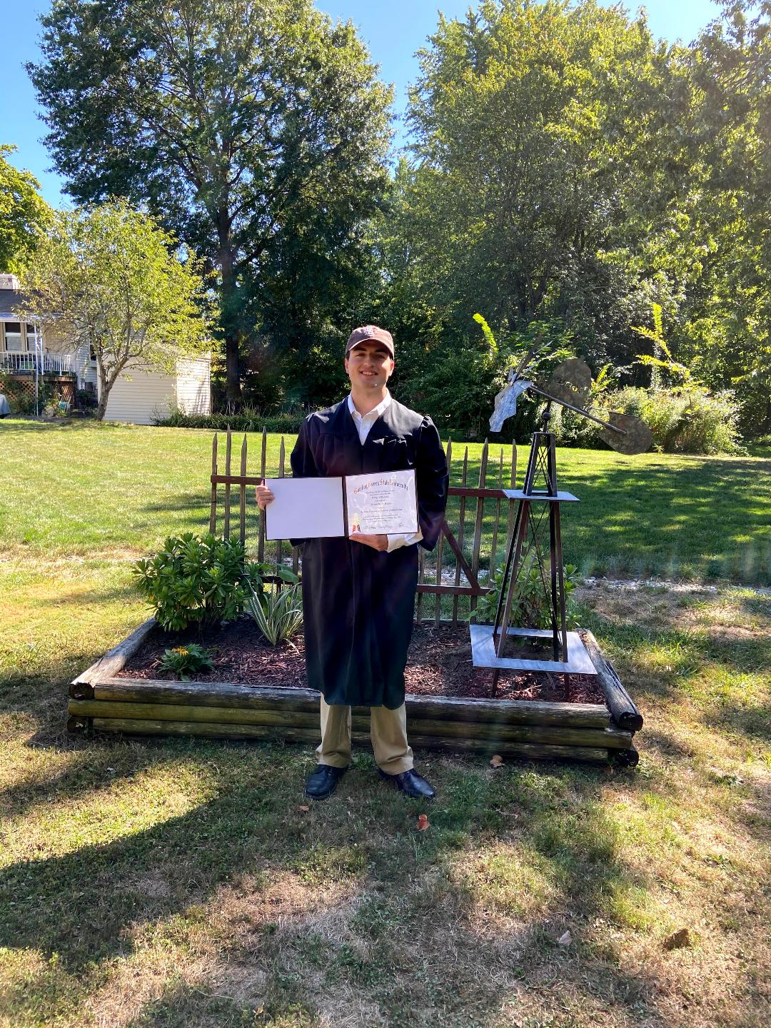 Mitch holding his diploma in a nice yard